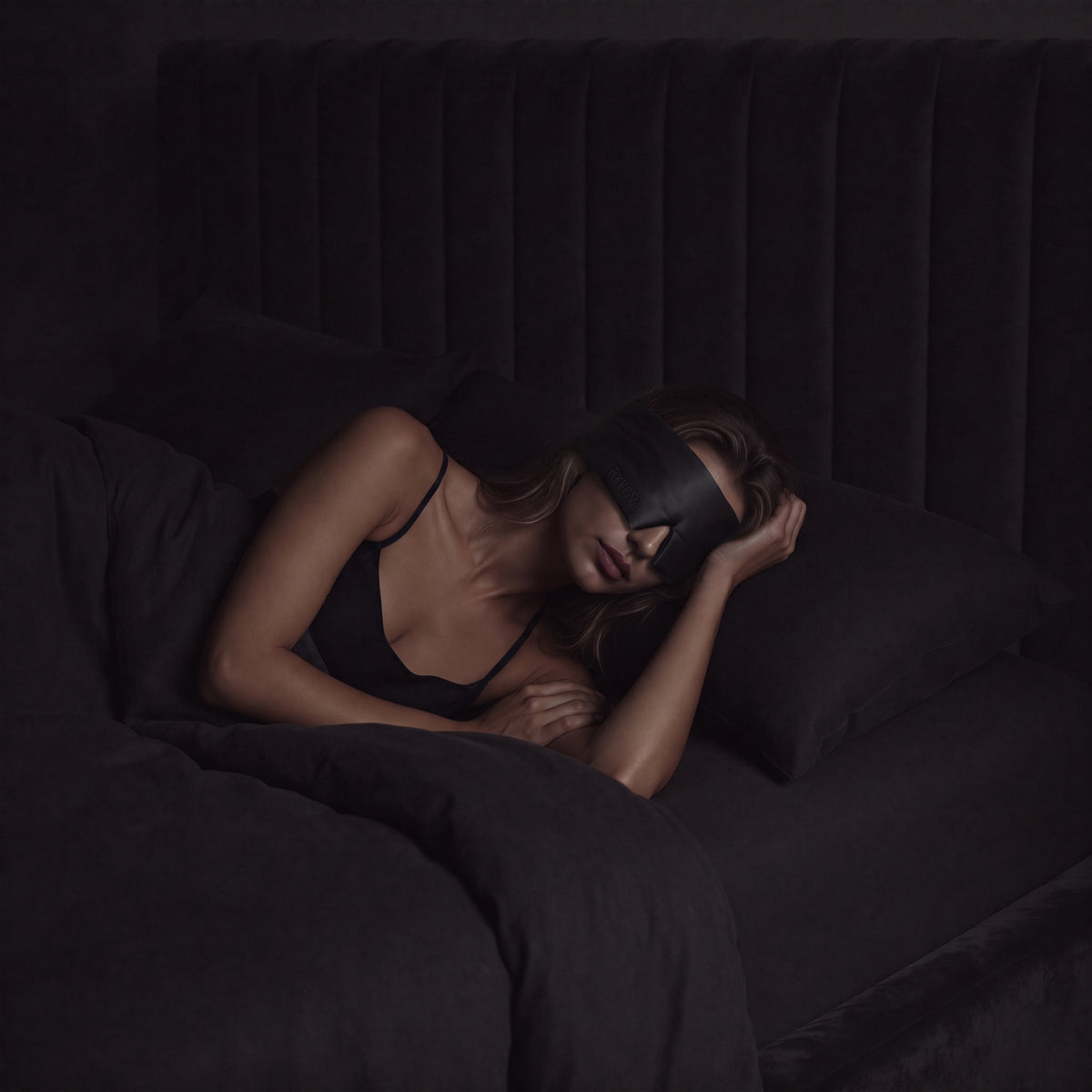 Woman sleeping wearing a RYVENA deep black silk sleep mask