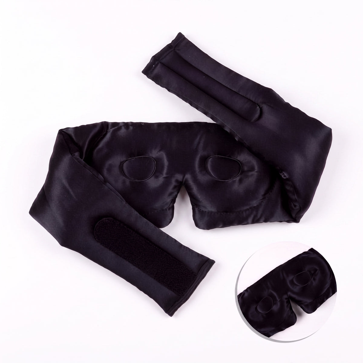 Deep black RYVENA silk sleep mask opened out, showing the full wide silk strap and contoured interior eye cups
