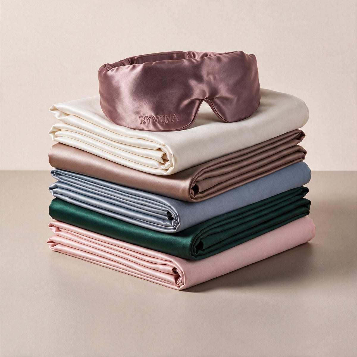 RYVENA Silk Ritual with blush pink silk sleep mask on a stack of silk pillowcases