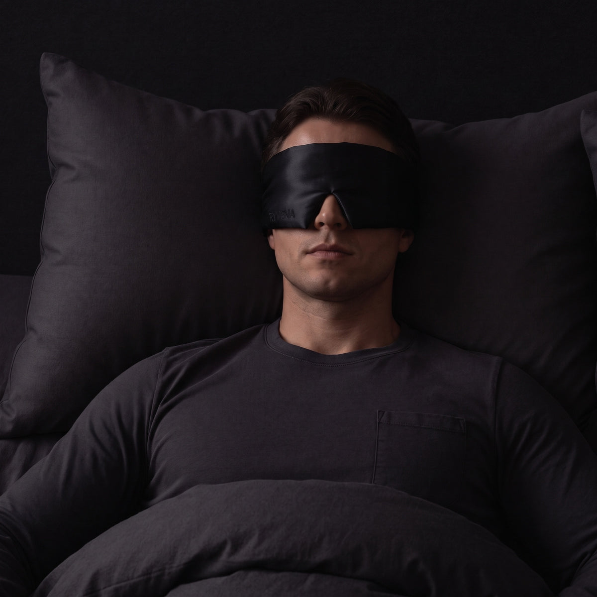 Man sleeping wearing a RYVENA deep black silk sleep mask