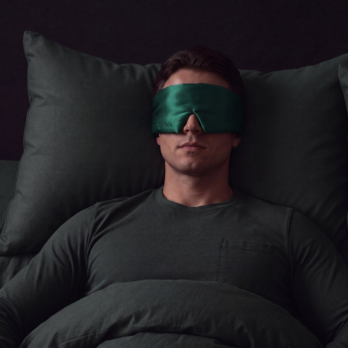 Man sleeping wearing a RYVENA emerald green silk sleep mask