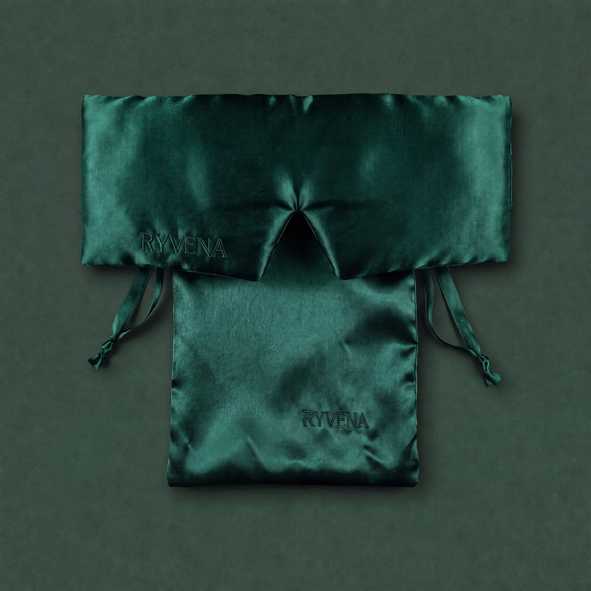 Emerald green RYVENA silk sleep mask resting on its branded silk carry bag