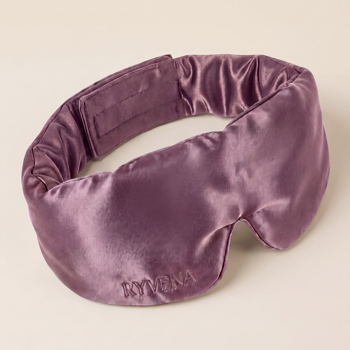 RYVENA contoured silk sleep mask in blush pink, angled to show the 22 momme mulberry silk face and tonal embroidery