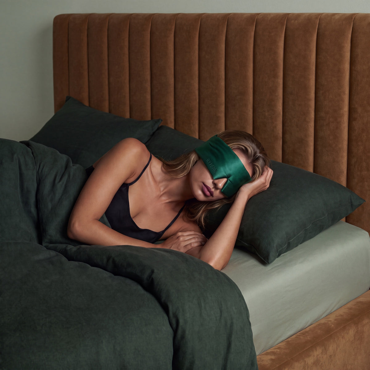 Woman sleeping wearing a RYVENA emerald green silk sleep mask